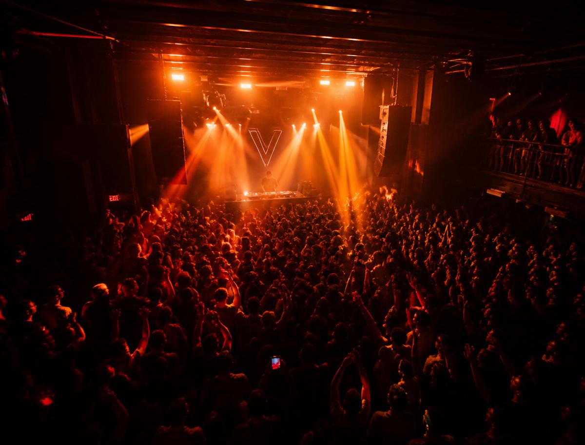 Packed dancefloor lit by orange stage beams